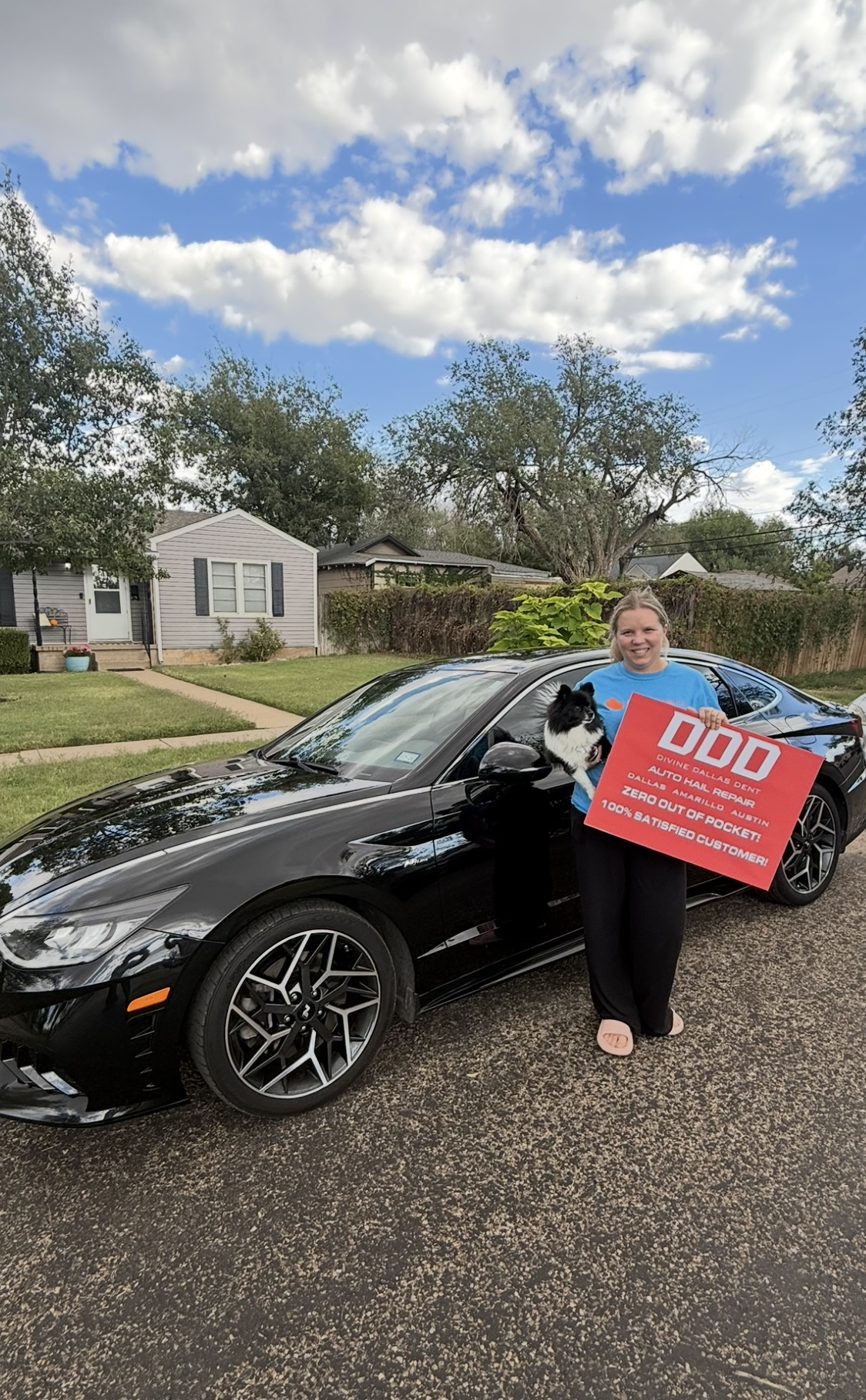Customer holding a Divine Dallas Dent sign next to her repaired black Genesis sedan