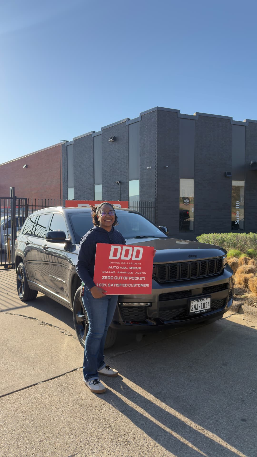 Customer holding a Divine Dallas Dent sign outside the Dallas, TX shop
